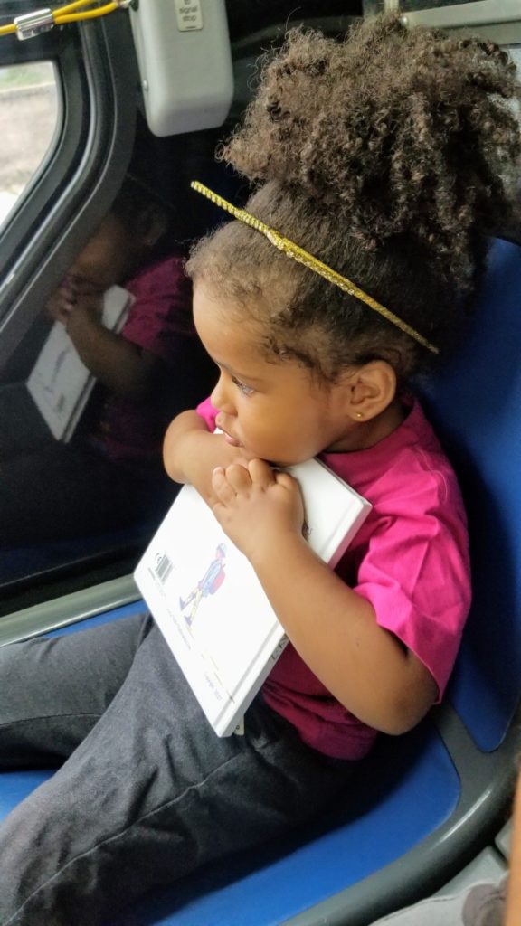 toddler hugging book MTA bus